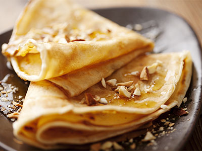 Crepes gefaltet und bestrichen mit Ahornsirup auf braunen Teller mit Nussstückchen im Da Roberto Café in Hachenburg im Habakuk