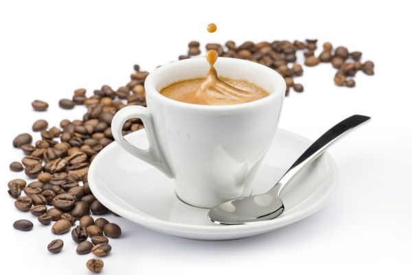 Espresso Ober- und Untertasse mit brauner Crema und braunen Kaffeebohnen vor weissem Hintergrund